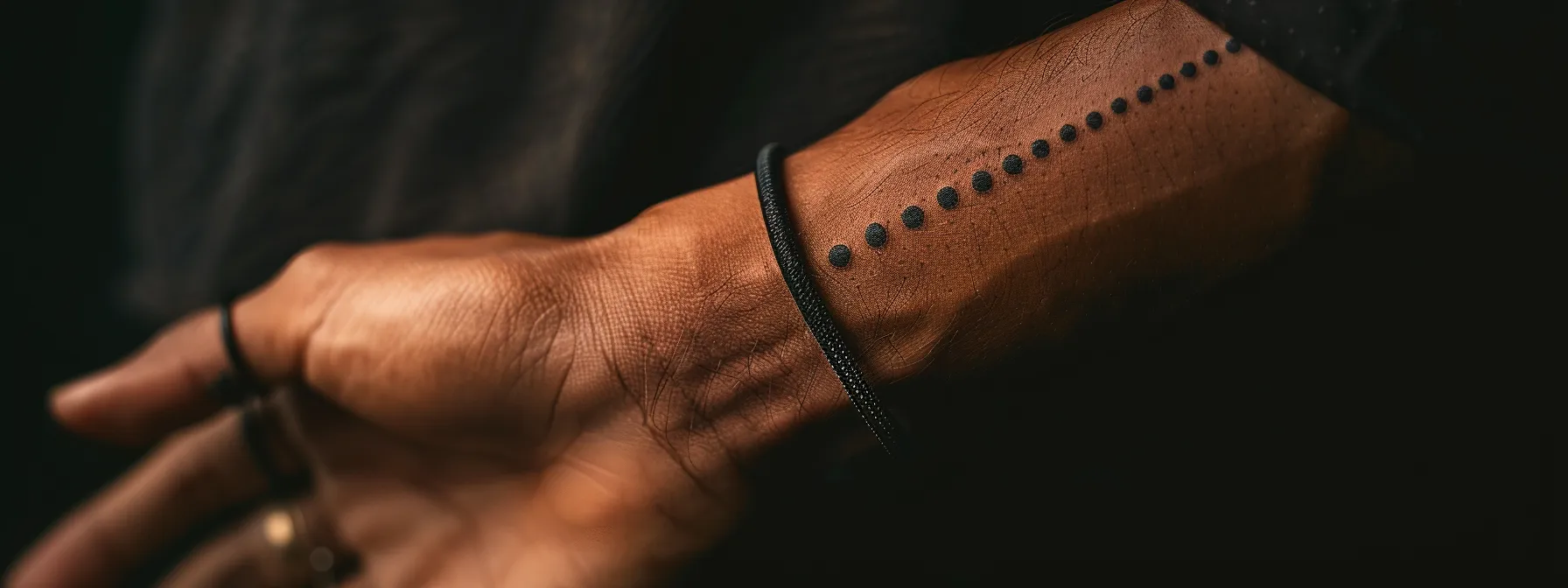 a close-up photo of a wrist adorned with a minimalist three dots tattoo, showcasing the precise placement and symbolic significance of the design.