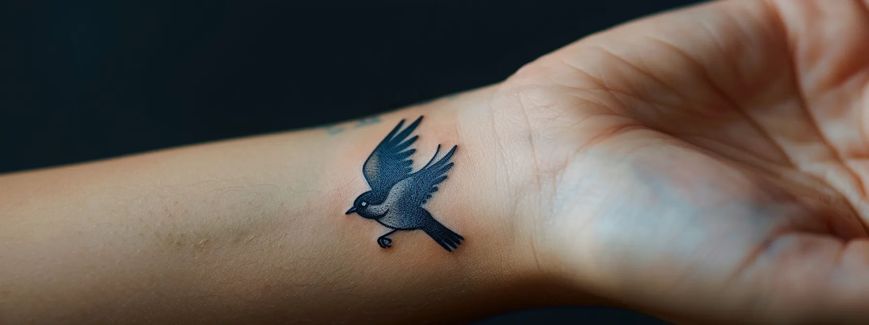 a small, delicate sparrow tattoo on a woman's wrist symbolizing freedom and grace.