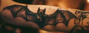 a striking black bat tattoo intricately detailed on someone's forearm.